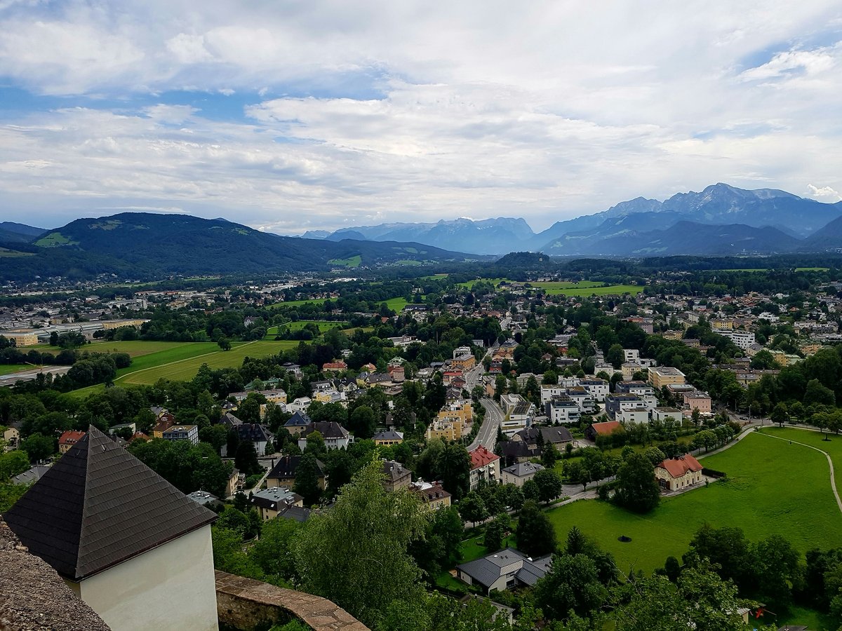 a scenic view of a town with mountains in the background