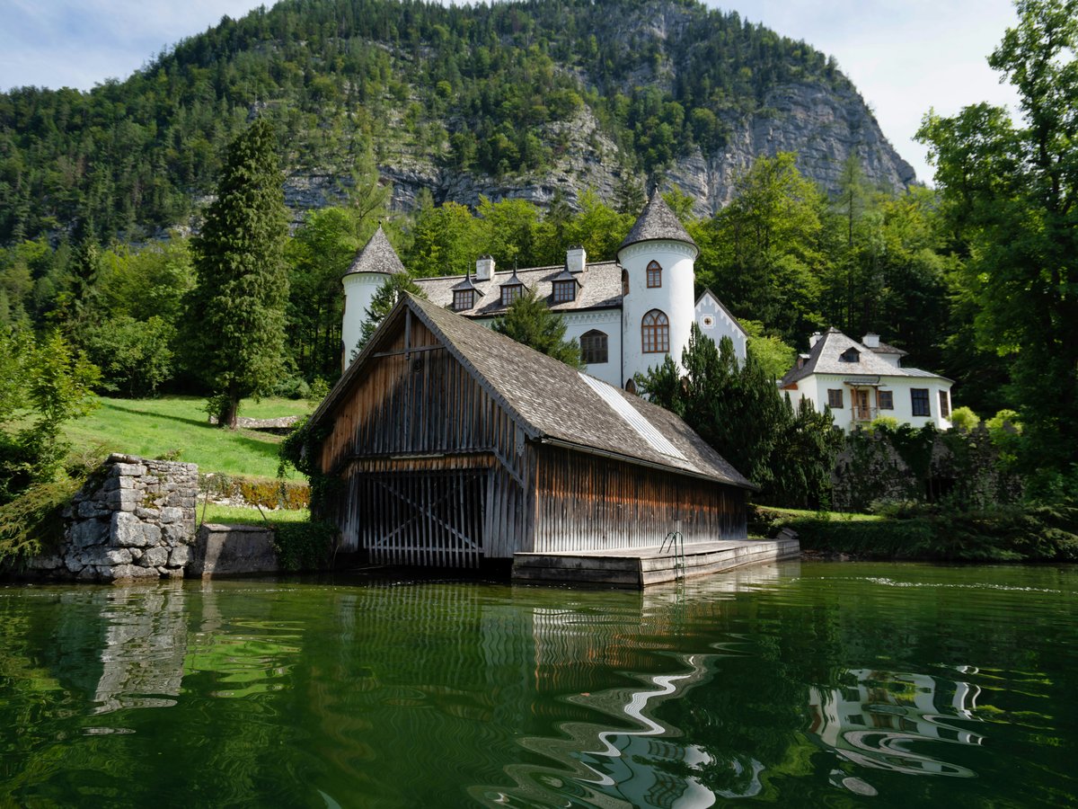 brown wooden house on green lake near green trees and mountain during daytime