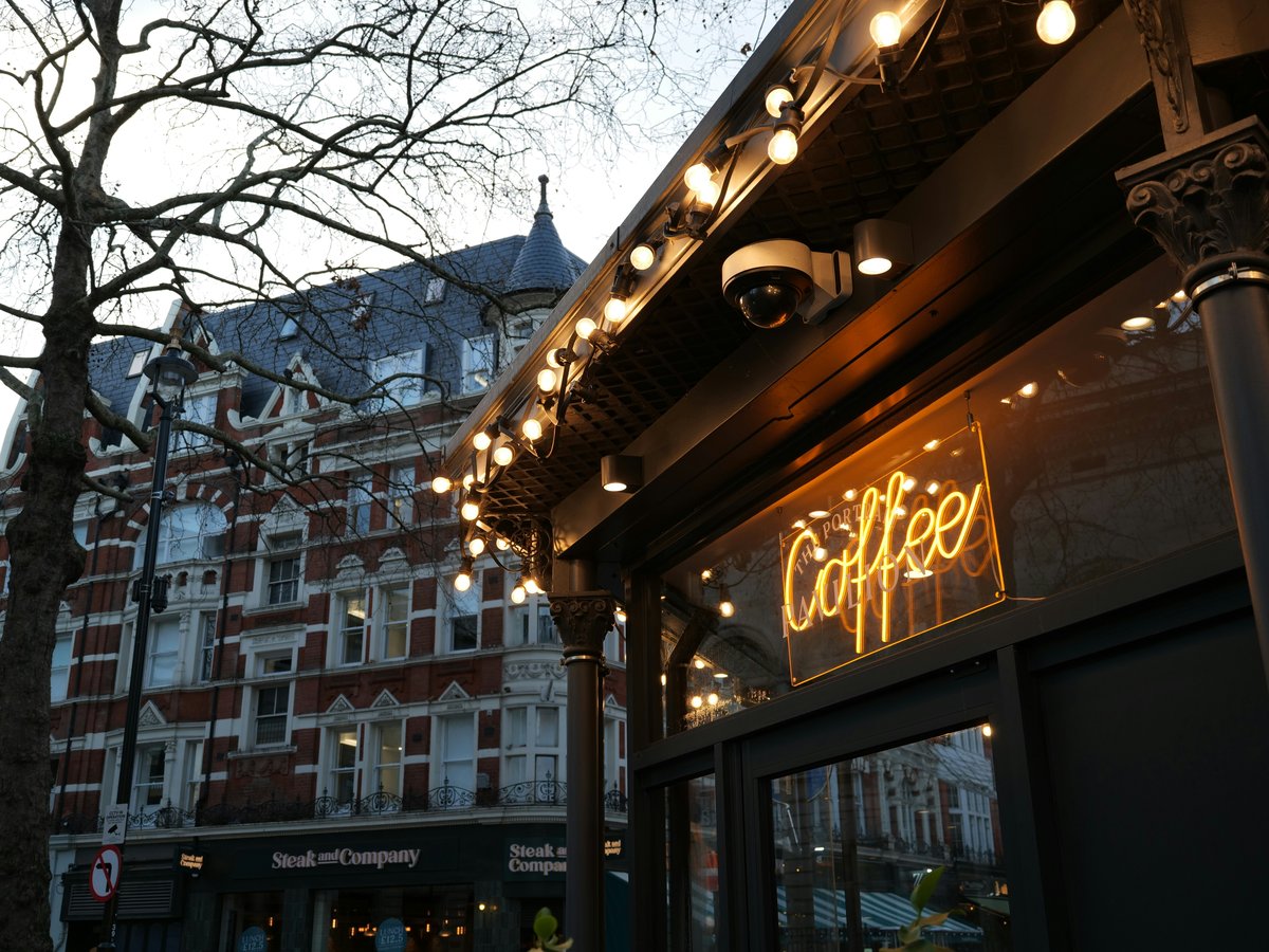 Coffee neon sign outside a cafe with festive lights.