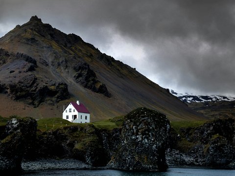 white house near brown mountain and body of water