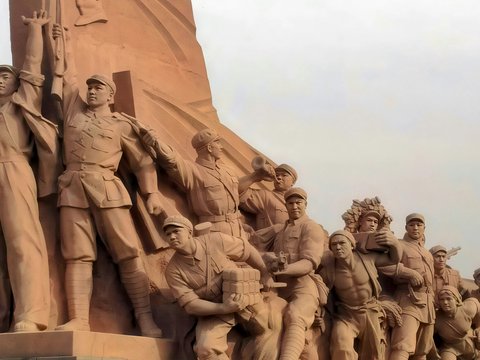 Monumental stone sculpture of marching figures in a procession