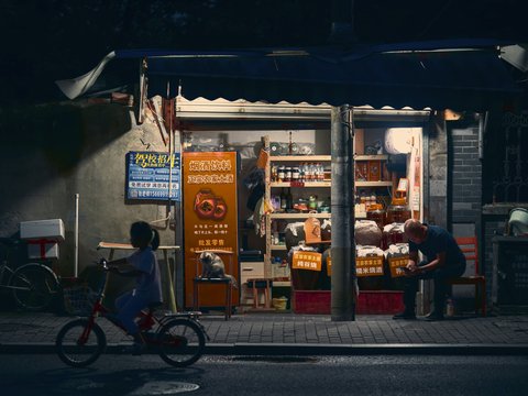 A child rides past a convenience store at night.