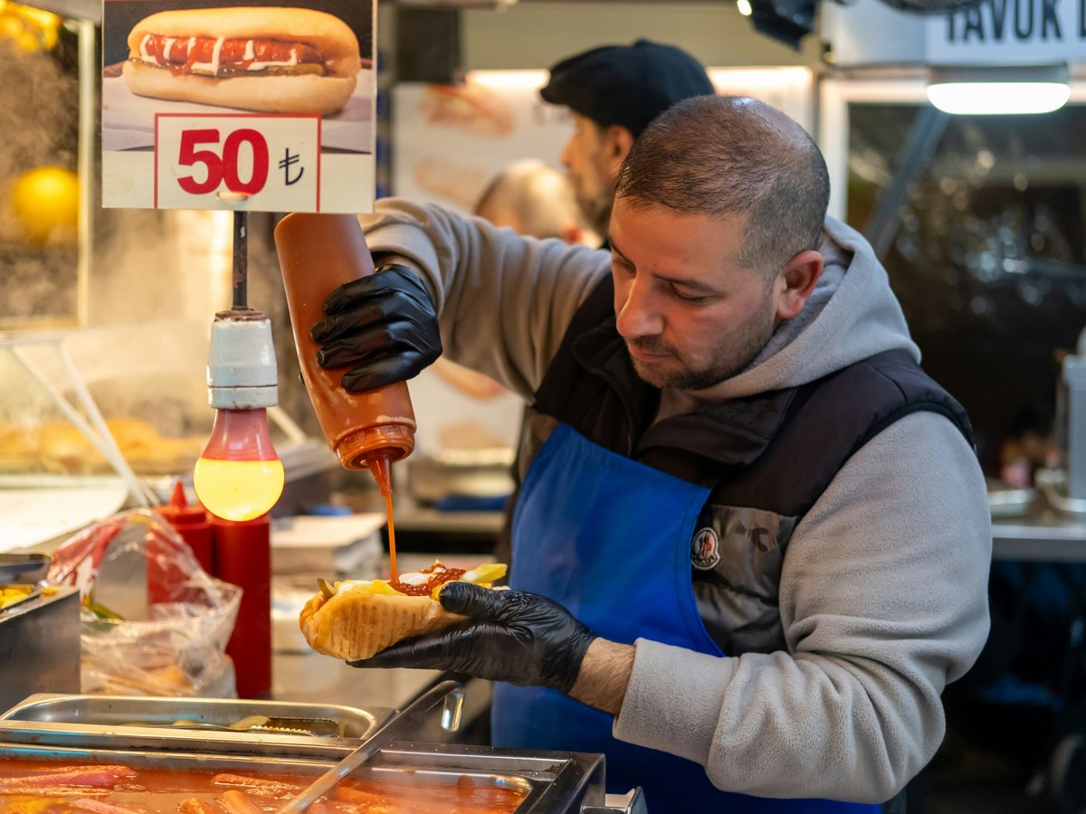 a man preparing food at a hot dog stand