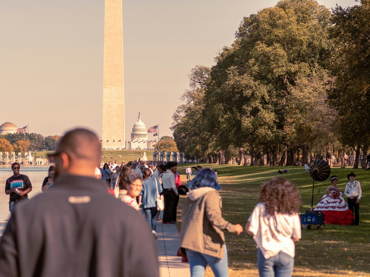 a group of people walking on a path with a monument in the background