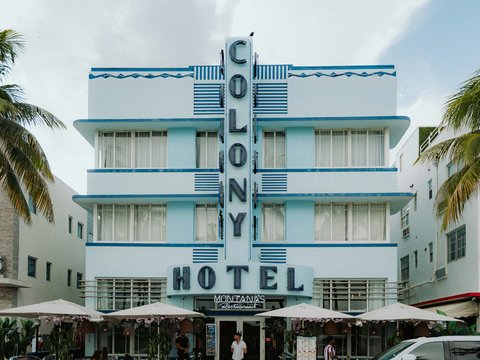 Light blue colony hotel building with art deco architecture.