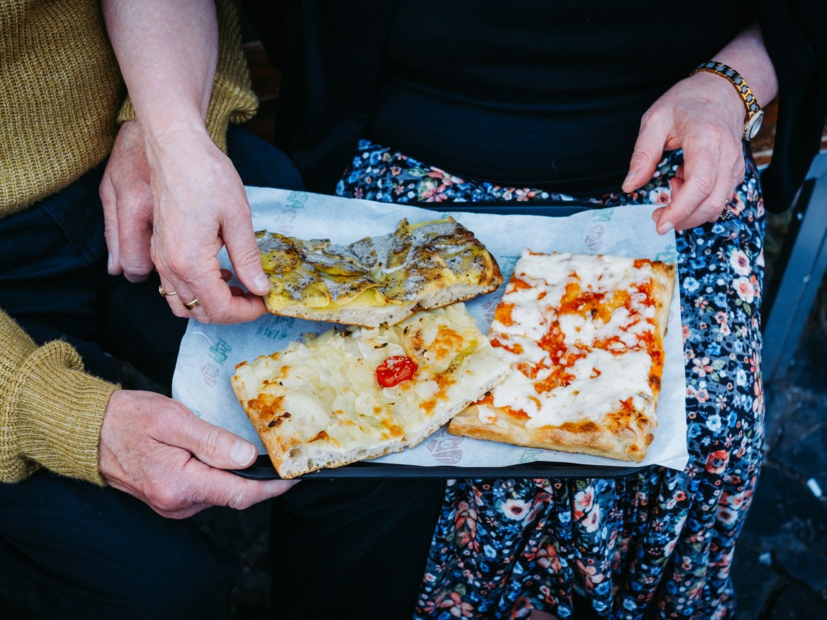 A woman holding a box of pizza on top of a table