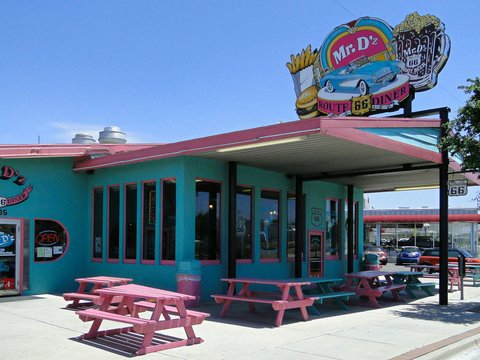 A blue and pink building with a pink picnic table outside of it