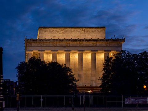 Lincoln memorial illuminated at dusk with cloudy sky.