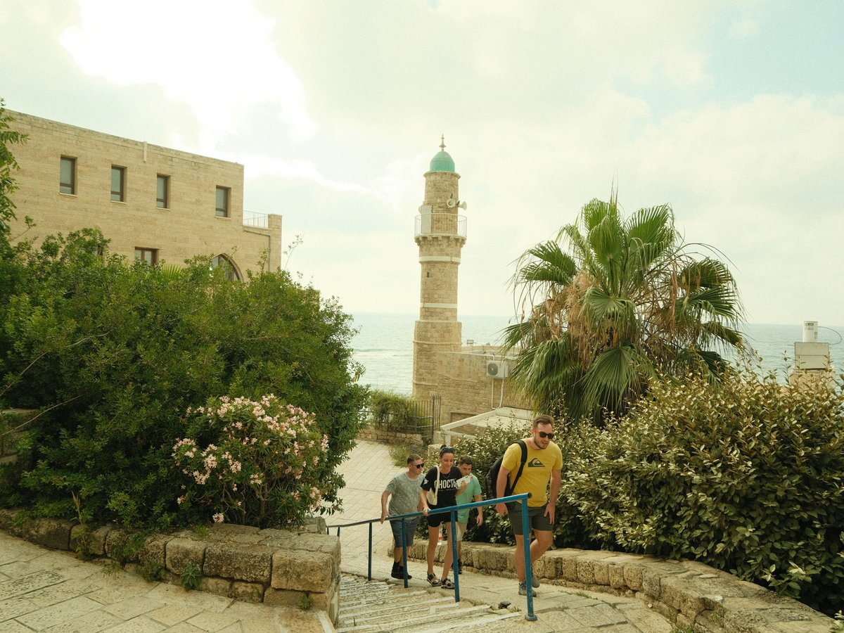 a group of people walking on a path by a building and trees