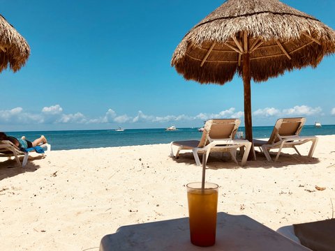 brown parasol and two beach chairs on beach sand