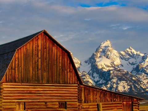 Wooden barn in front of snow-capped mountains