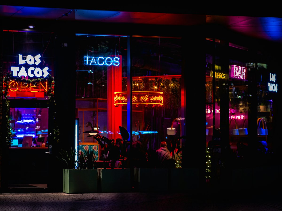 A taco shop lit up at night with neon lights