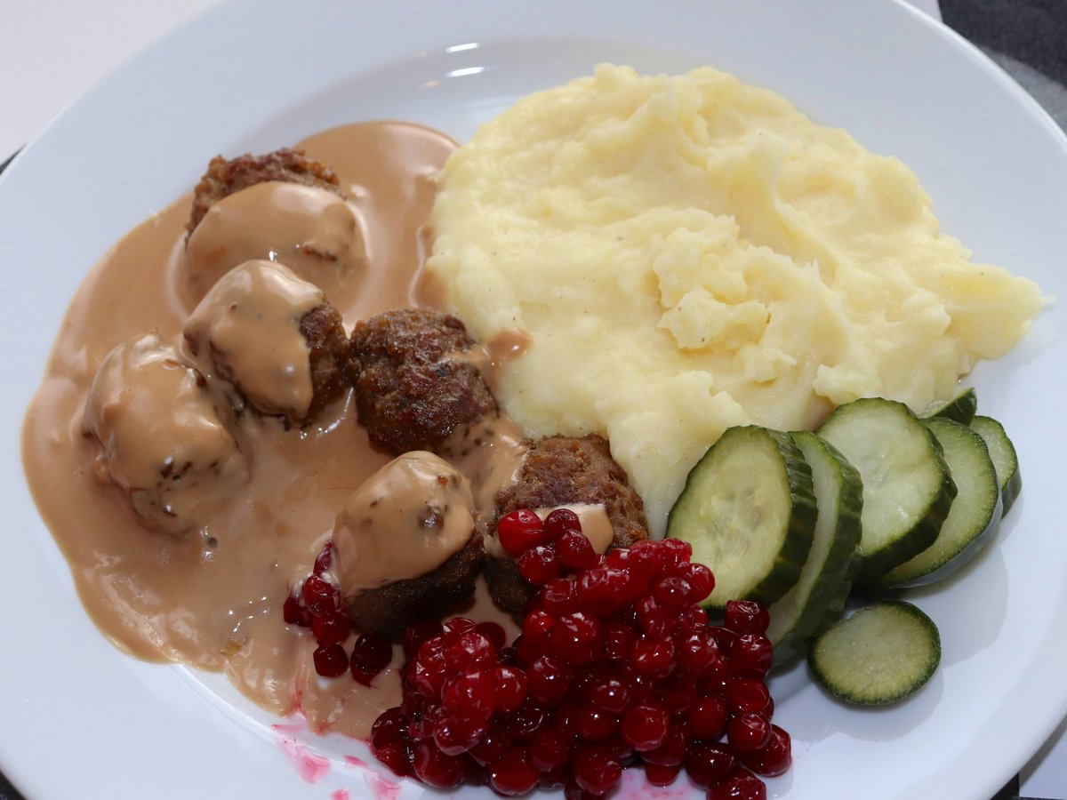 a white plate topped with meatballs, mashed potatoes and cucumbers