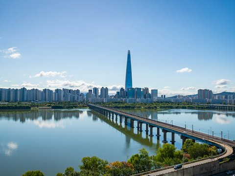 Modern cityscape with a tall skyscraper and bridge over river