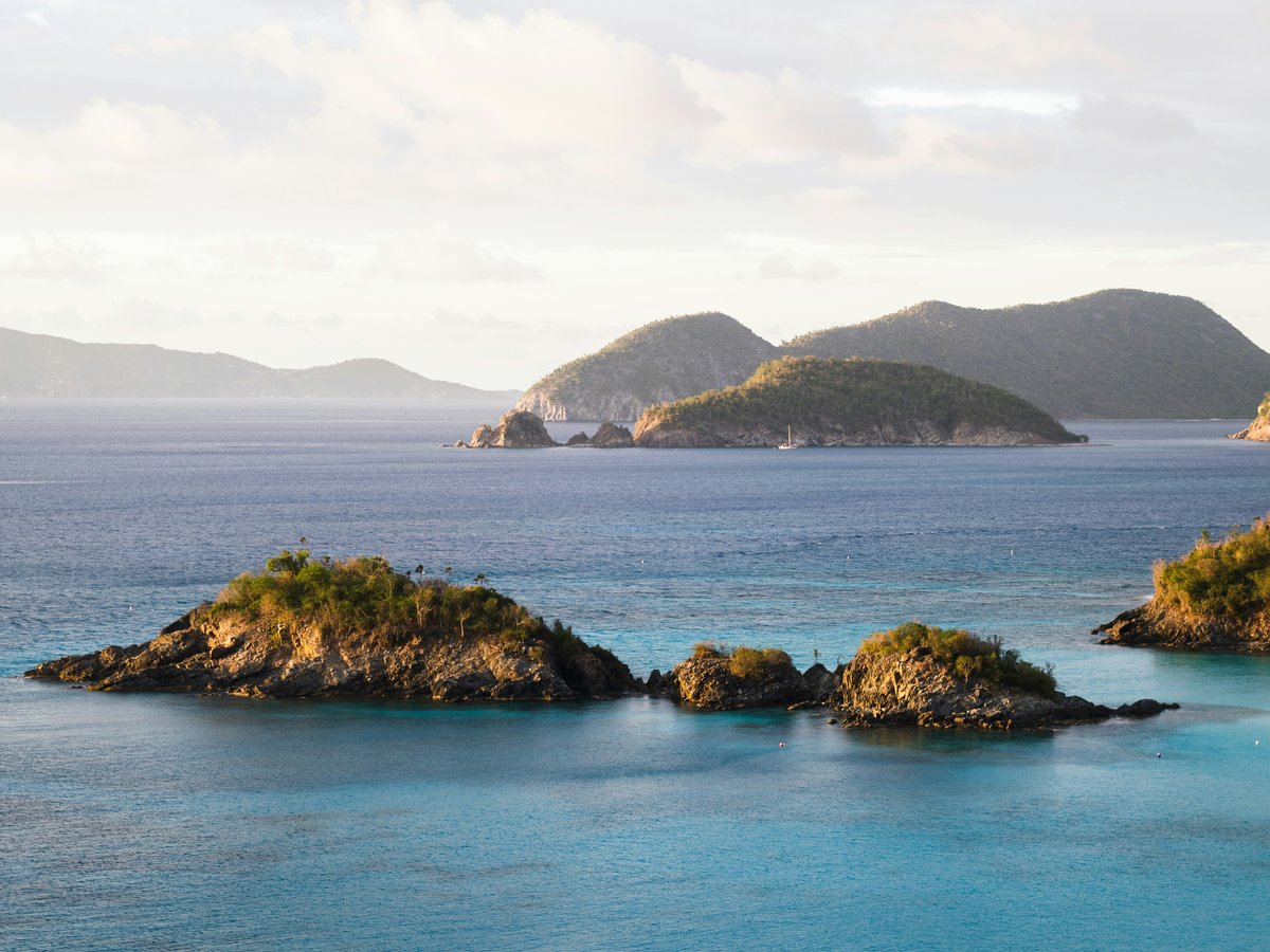 brown and green island on blue sea under white clouds during daytime