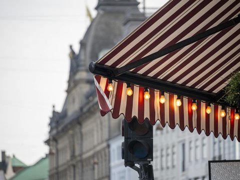 Red and white striped awning with lights above street