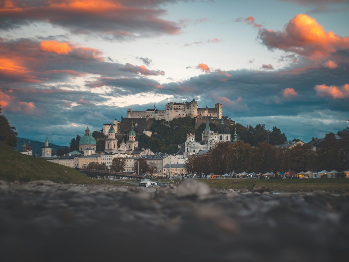 village below castle under cloudy sky during golden hour