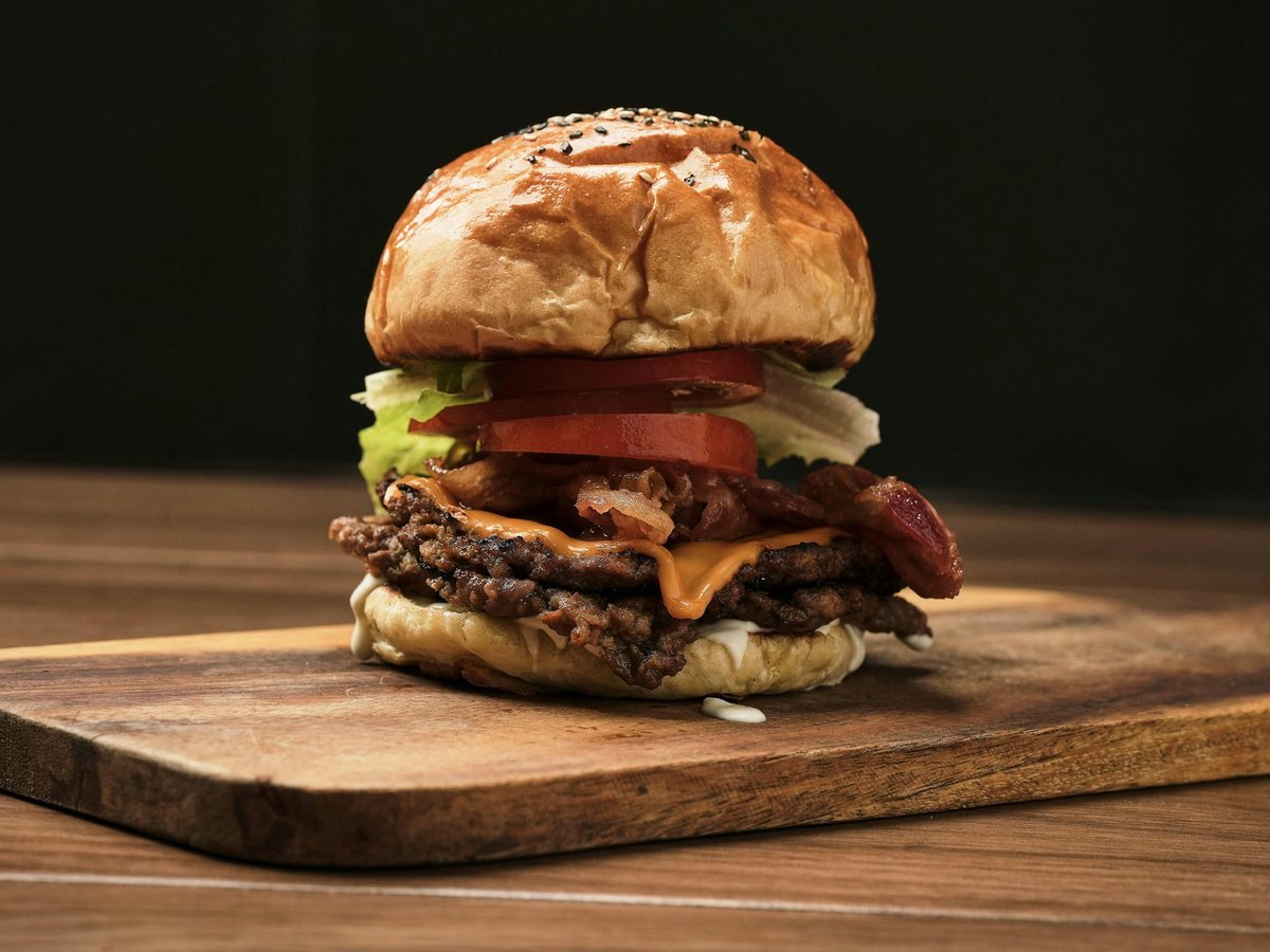 A large hamburger sitting on top of a wooden cutting board