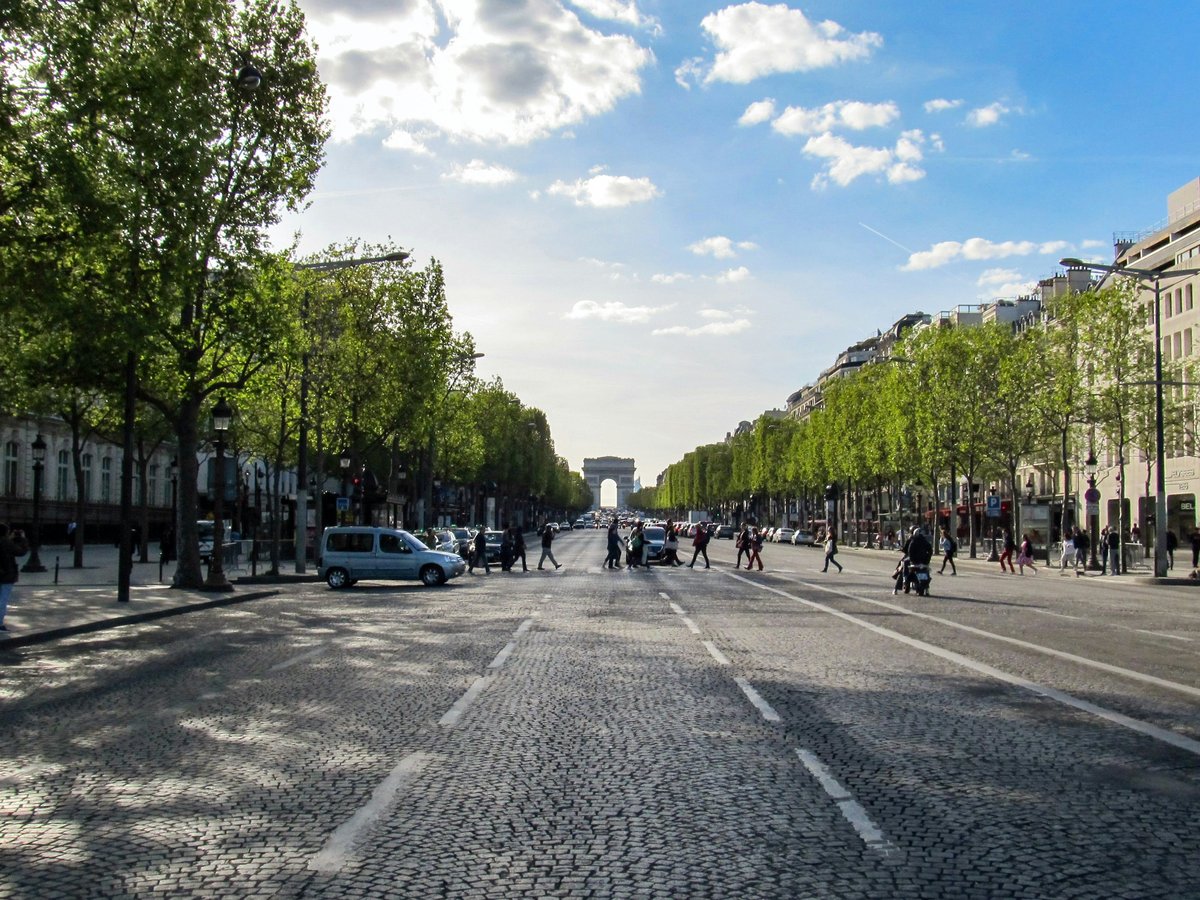 a street with trees and buildings on the side with Champs-Élysées in the background