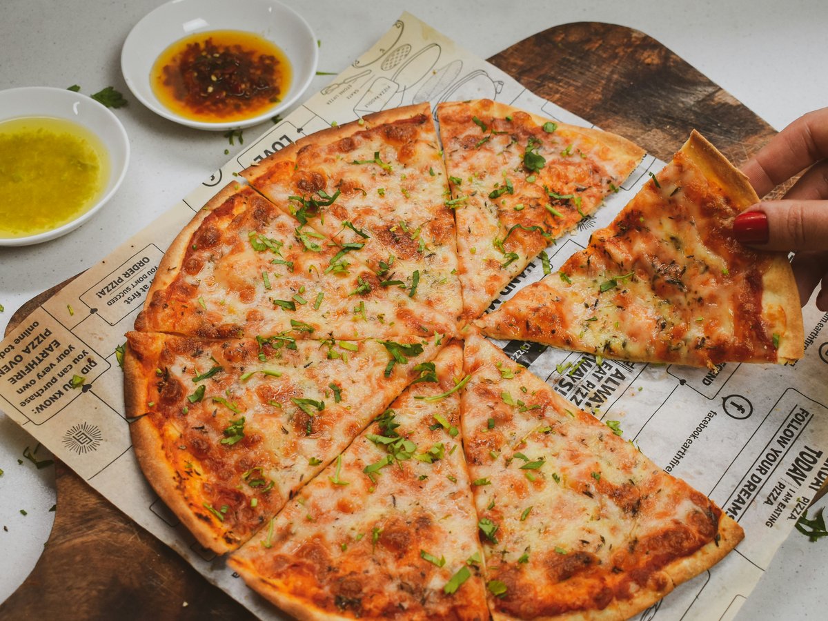 a person holding a slice of pizza on top of a piece of paper