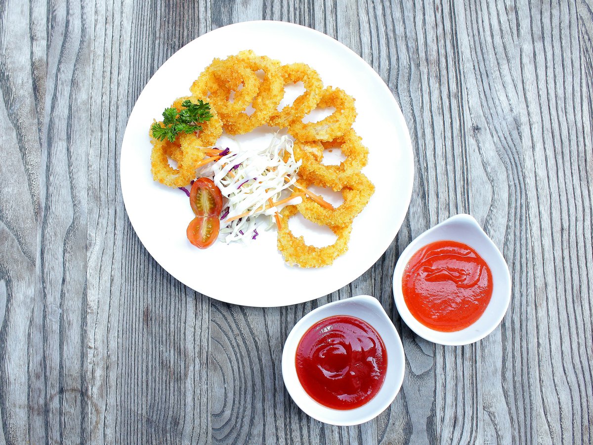 a white plate topped with onion rings and ketchup