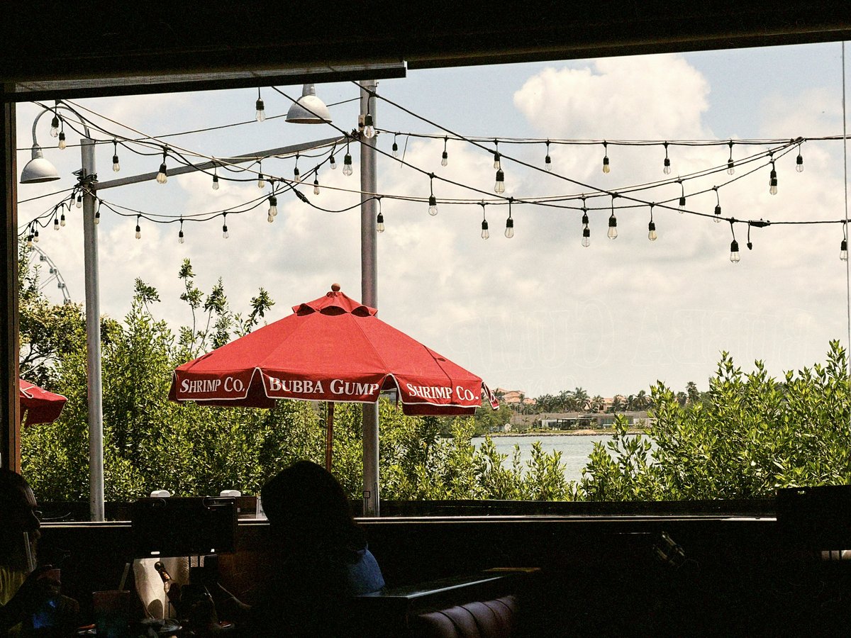 Restaurant patio with string lights, red umbrella, lake view.