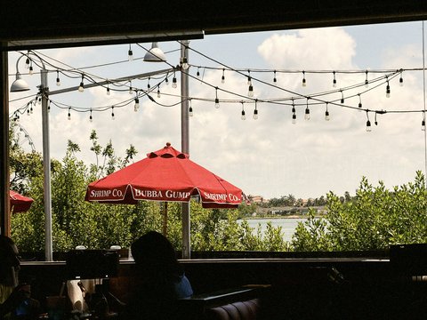 Restaurant patio with string lights, red umbrella, lake view.