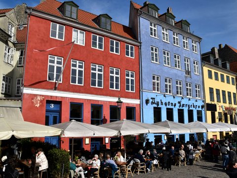 A group of people sitting at tables in front of buildings