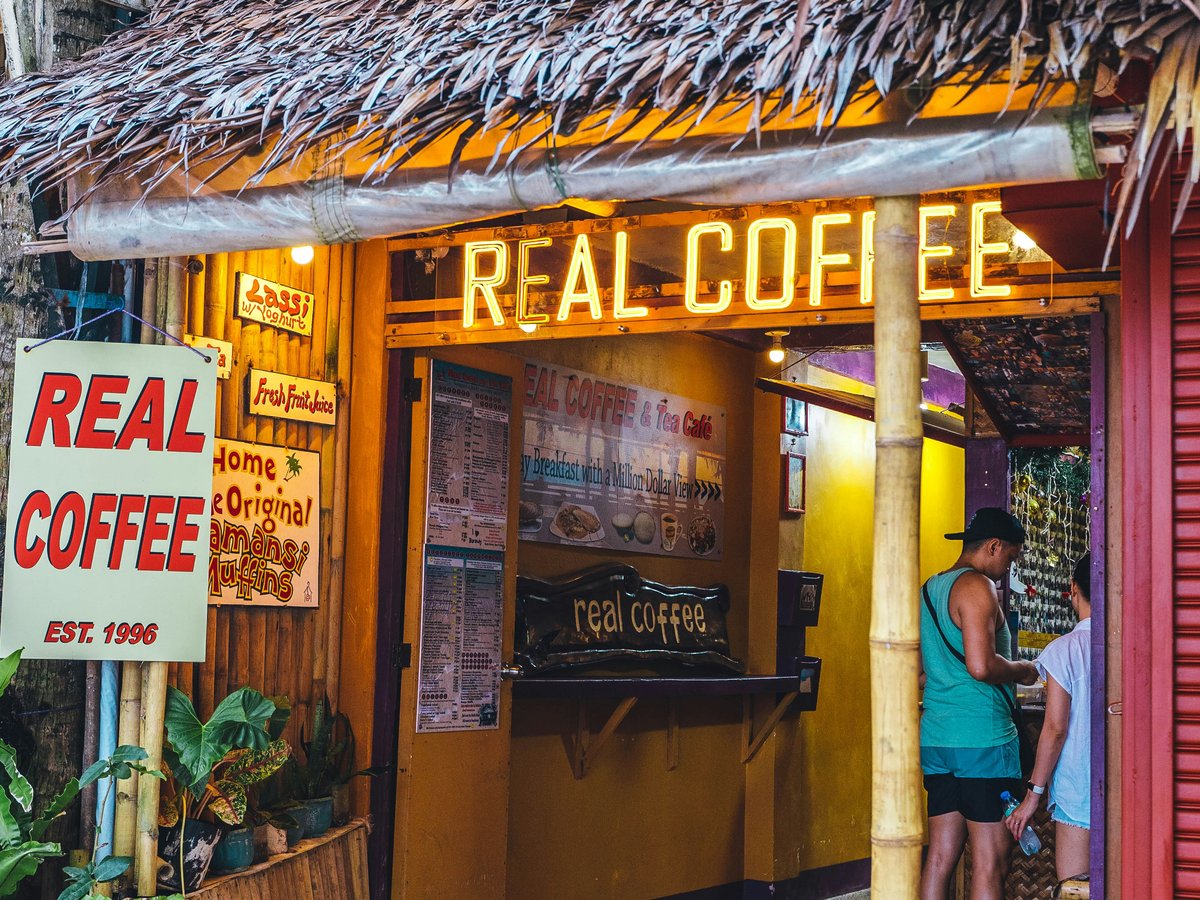 a couple of people standing outside of a coffee shop