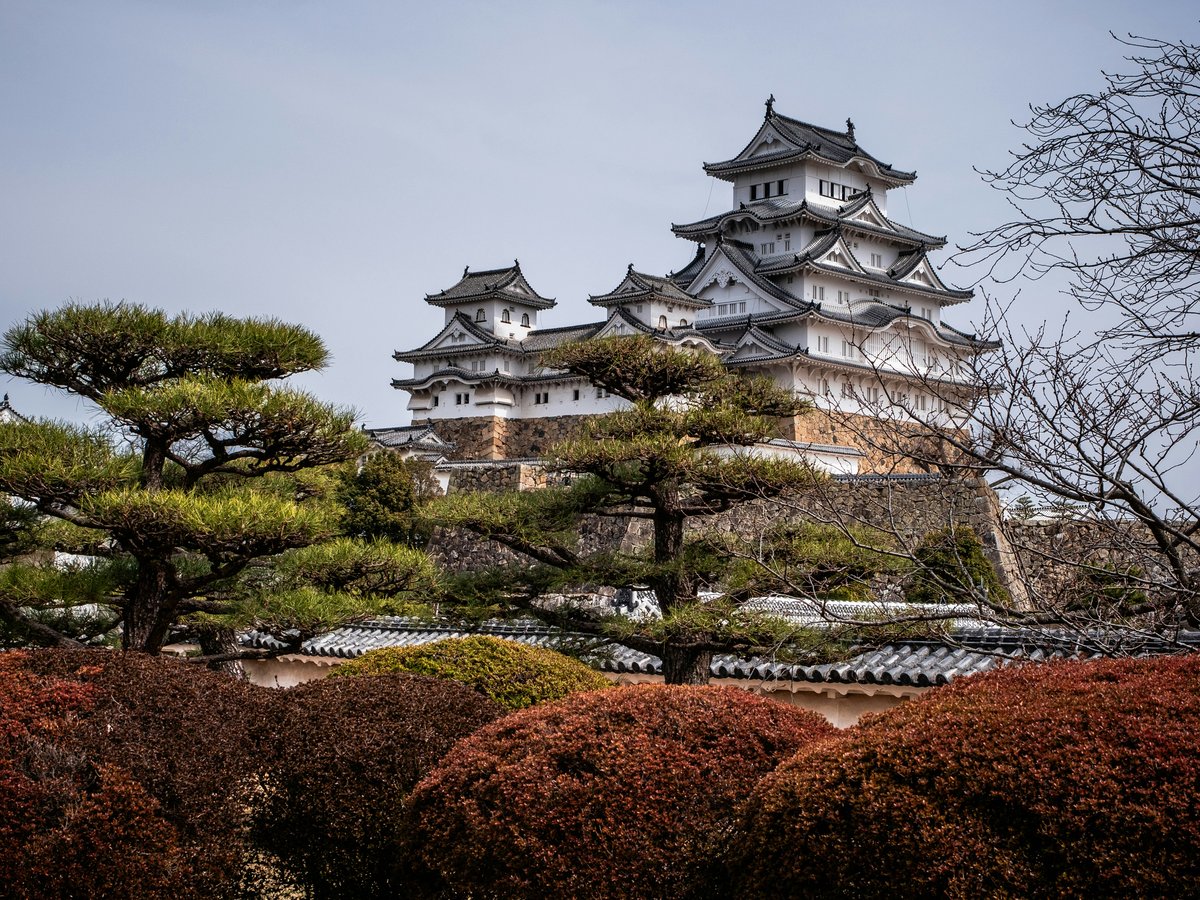 a tall white building sitting on top of a lush green hillside