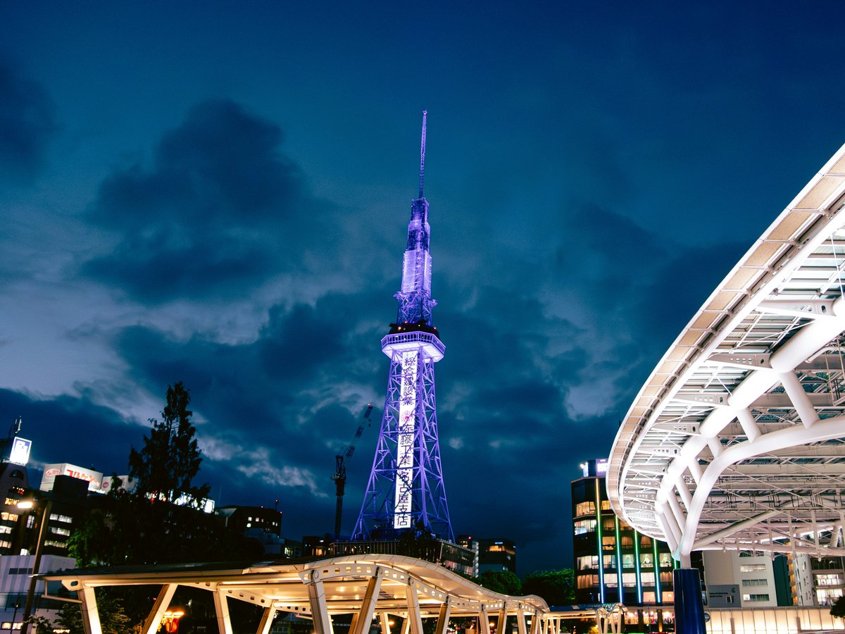 Illuminated purple tower and modern structures under a dark sky