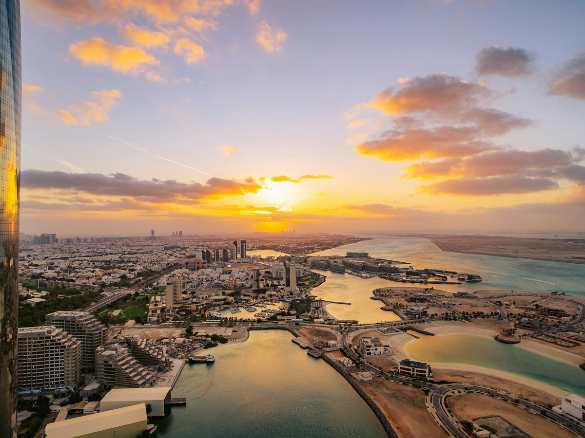the sun is setting over a city and a body of water