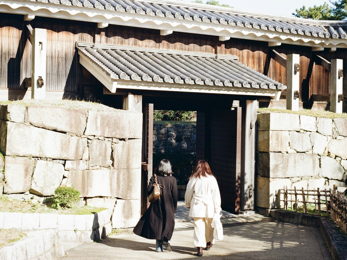 Two people walk through a historic castle gate