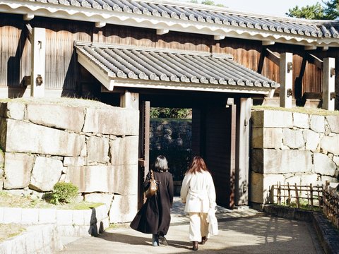 Two people walk through a historic castle gate