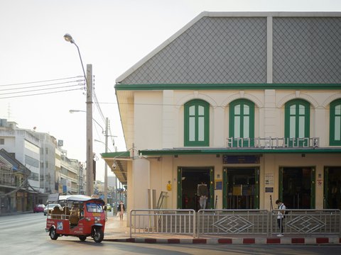 a red car driving down a street next to a tall building