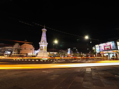 a city street at night with a clock tower in the background