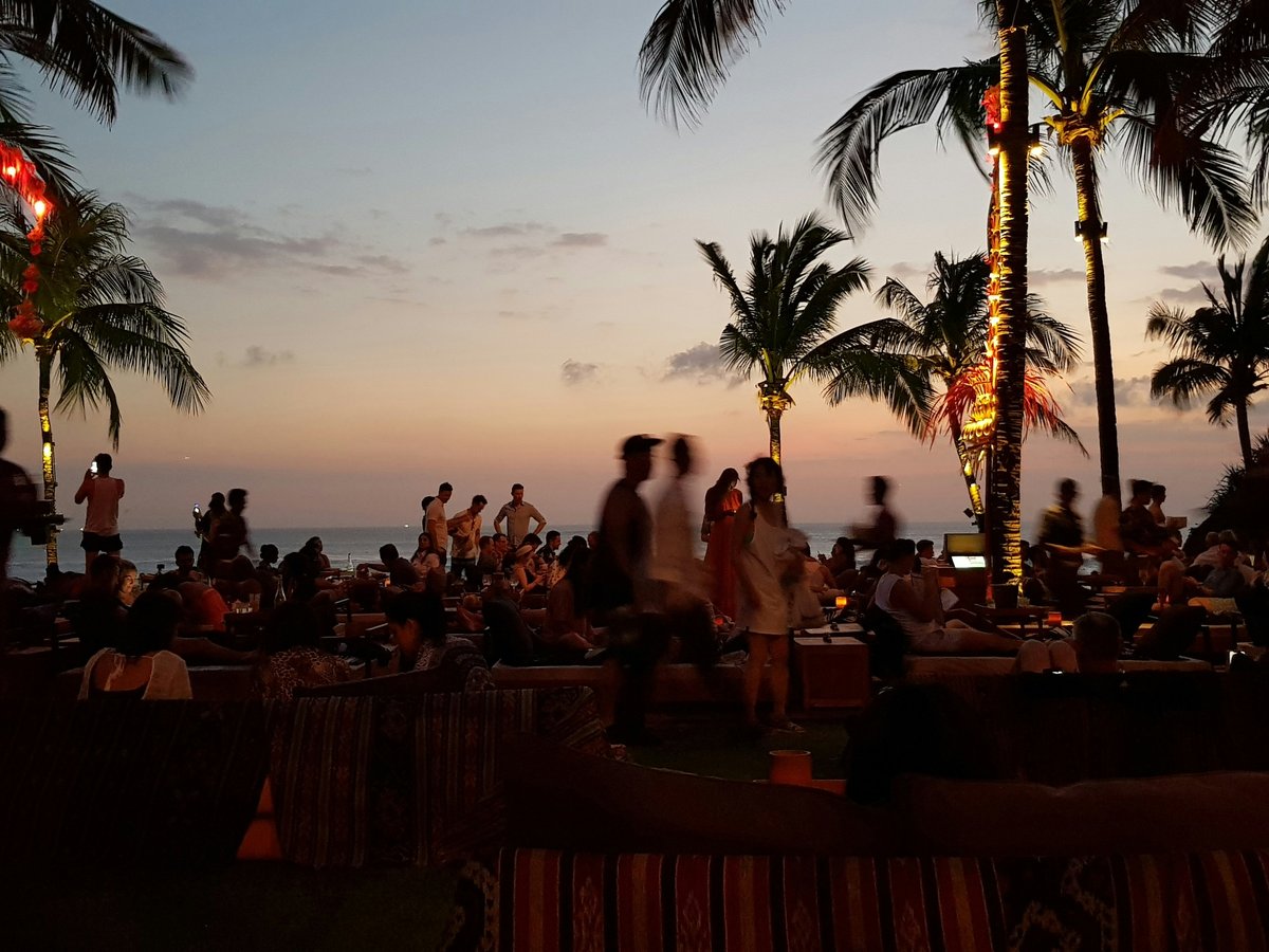 a group of people sitting on a beach at sunset