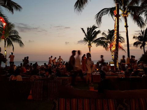 a group of people sitting on a beach at sunset