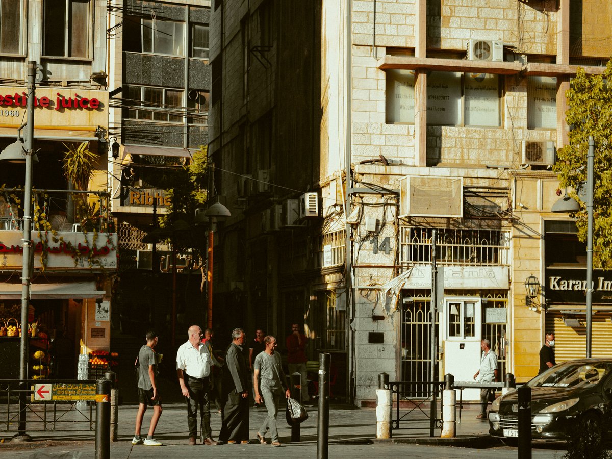 A group of people walking down a street next to tall buildings