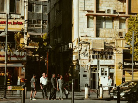 A group of people walking down a street next to tall buildings