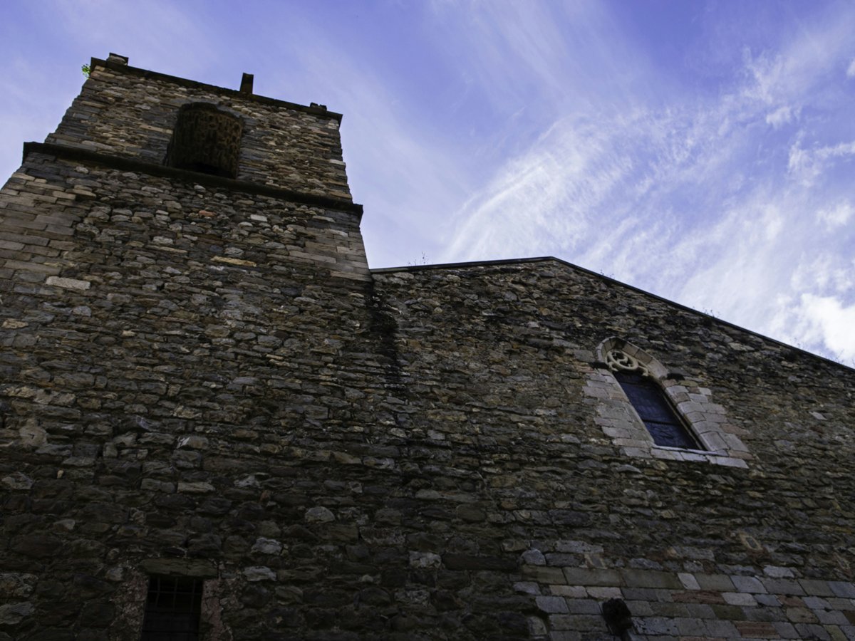 Old stone church with a bell tower under blue sky.
