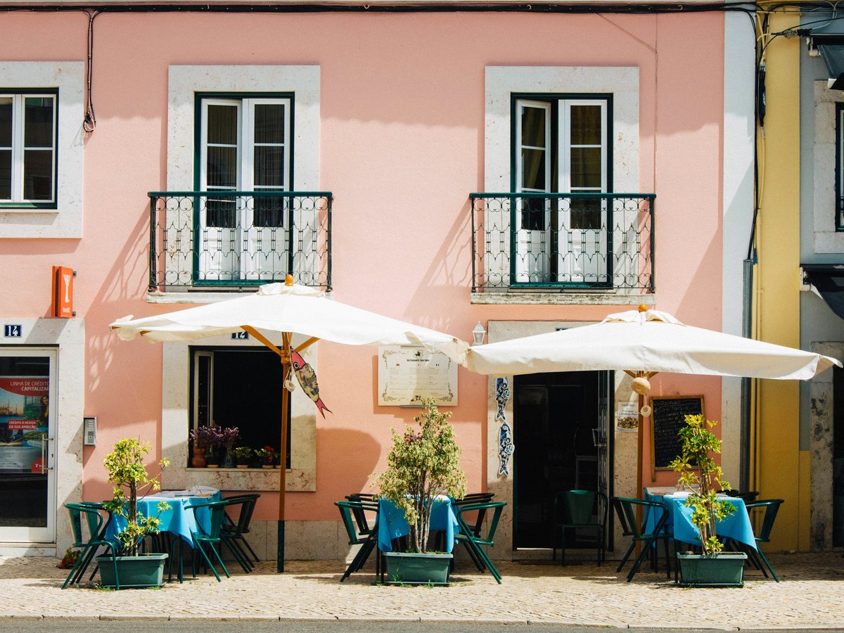 two white patio umbrellas near pink and white painted concrete building
