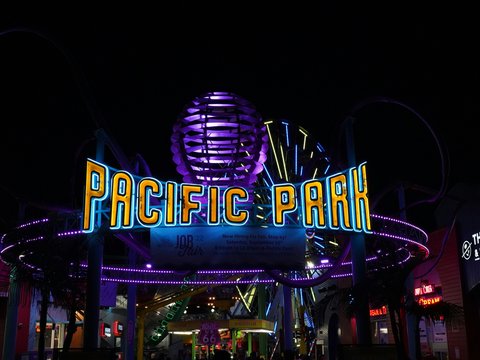 a neon sign with a ferris wheel in the background