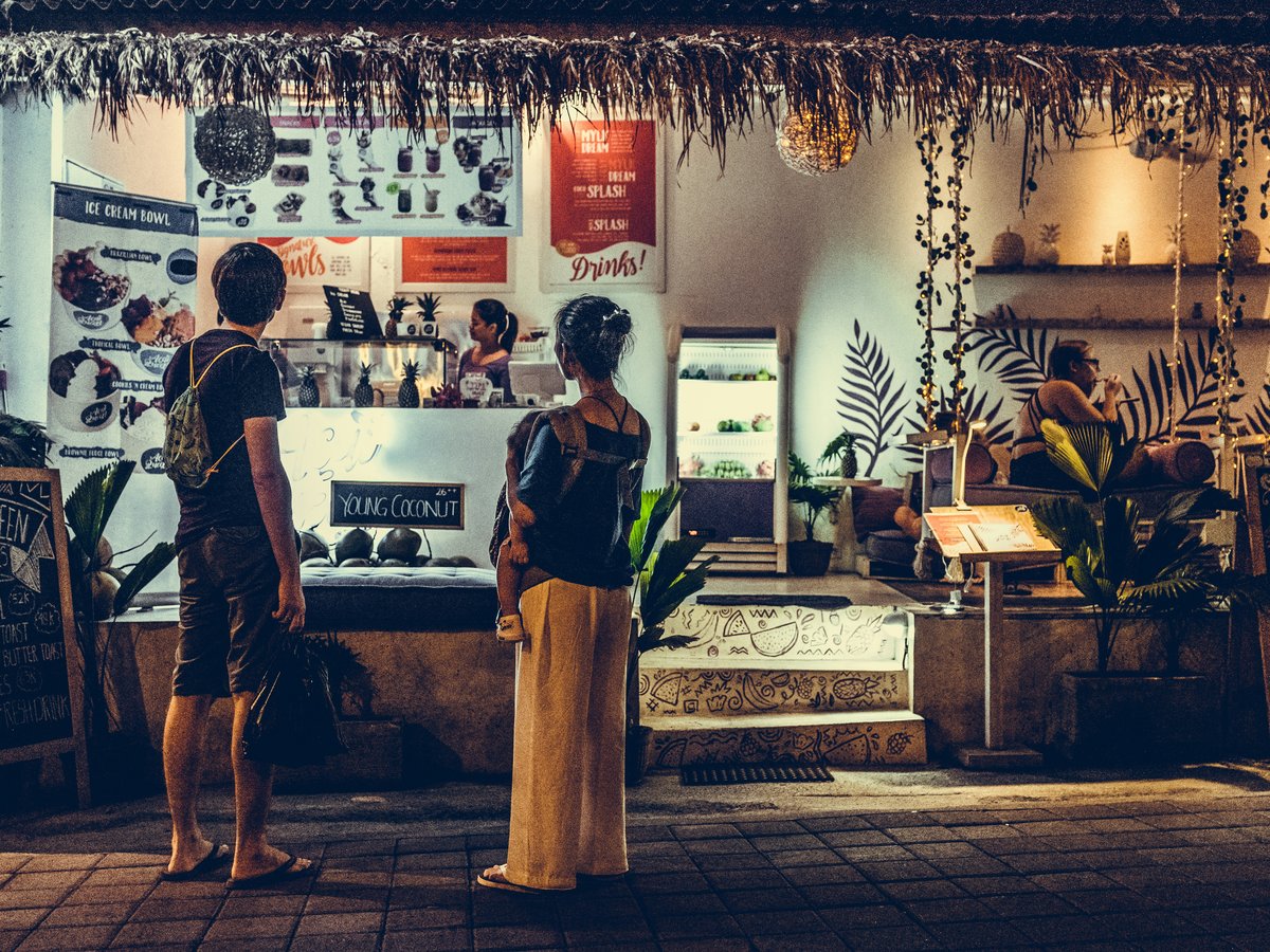 woman carrying a baby standing in front of store