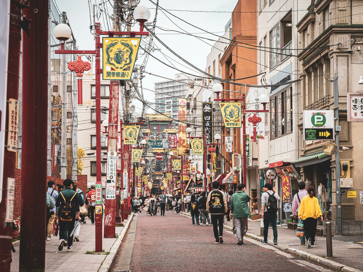 A group of people walking down a street next to tall buildings
