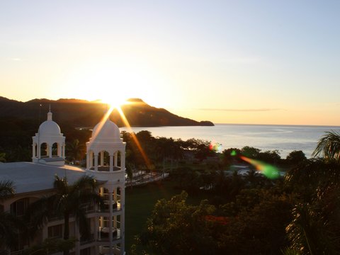 the sun is setting over the ocean and mountains