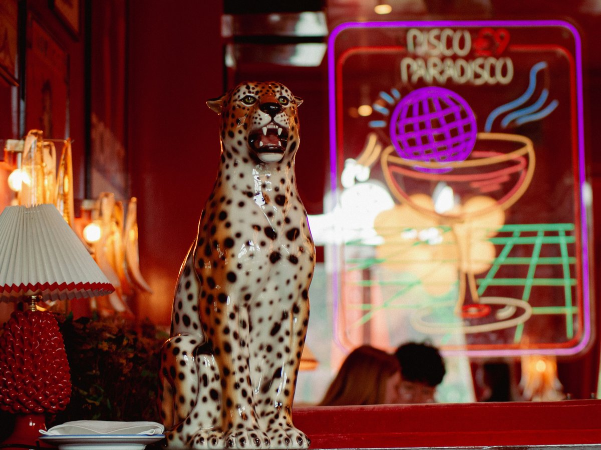 An ornate jaguar statue stands near a neon sign.