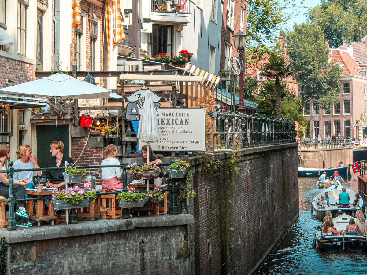 a group of people sitting at tables next to a river