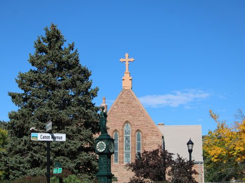 Stone church with cross against blue sky.