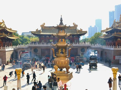 People gather at a temple with a large incense burner.
